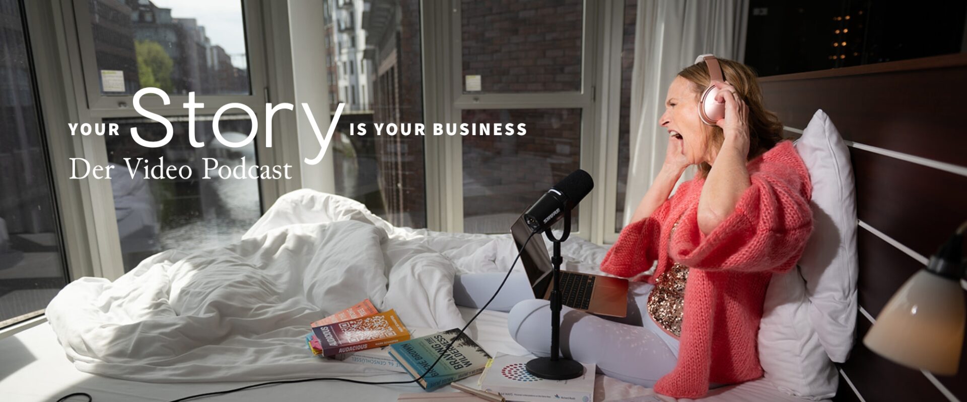 Iris Seng, Business Story Architect und Mentorin für kreative Solopreneurinnen, bei der Aufnahme ihres Podcasts ‚Your Story is Your Business‘ in einem Hotelzimmer mit Blick auf die Hamburger Fleete – umgeben von inspirierenden Büchern, Charts und Ideen.